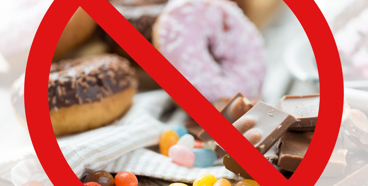 Donuts, chocolates and jelly beans behind a NO symbol